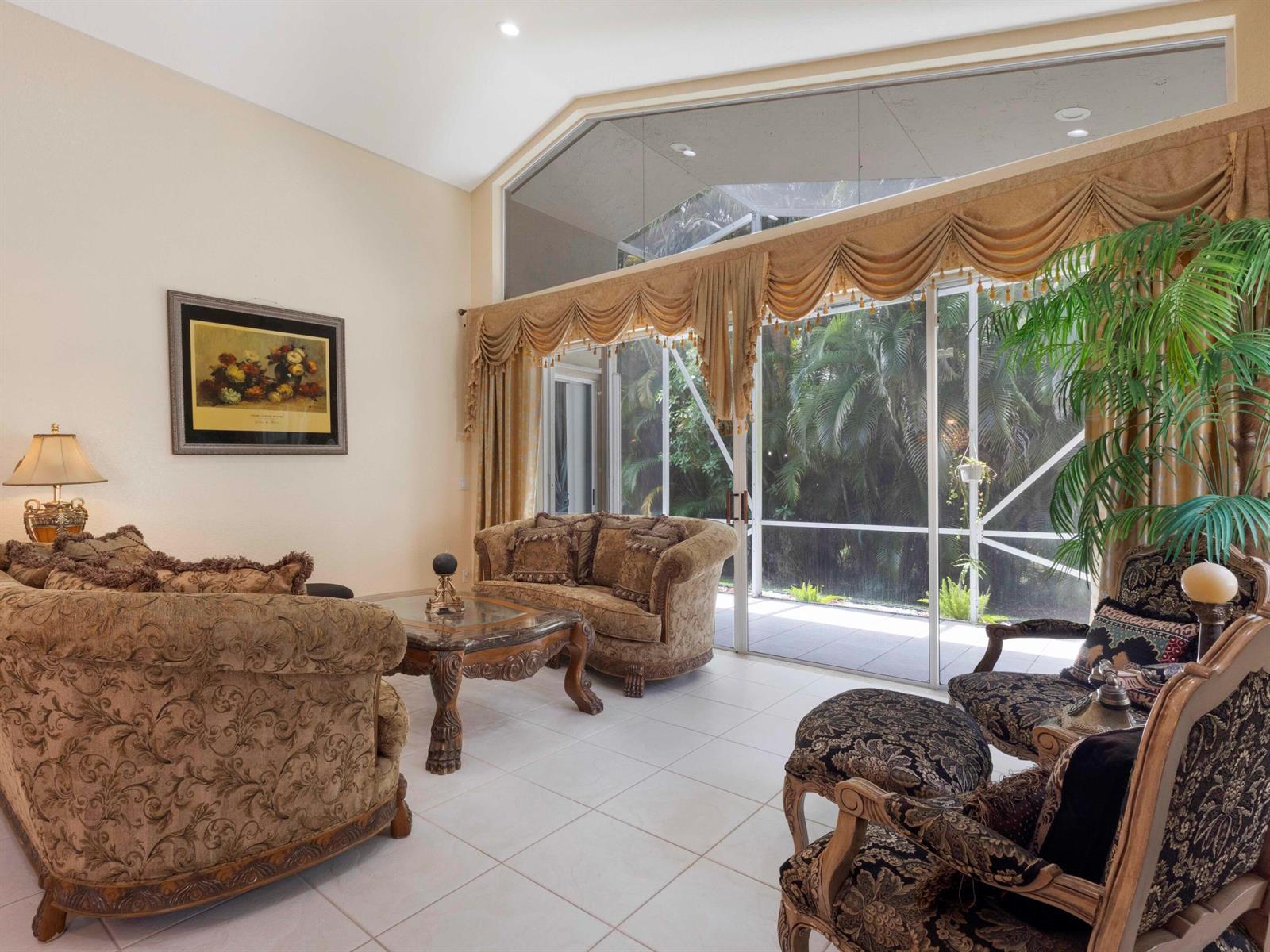 A living room with vaulted ceilings, tiled floors, ornate furniture, and large sliding glass doors — 5159 Brookview Drive, Boynton Beach FL 33437, BOYNTON BEACH, FL
