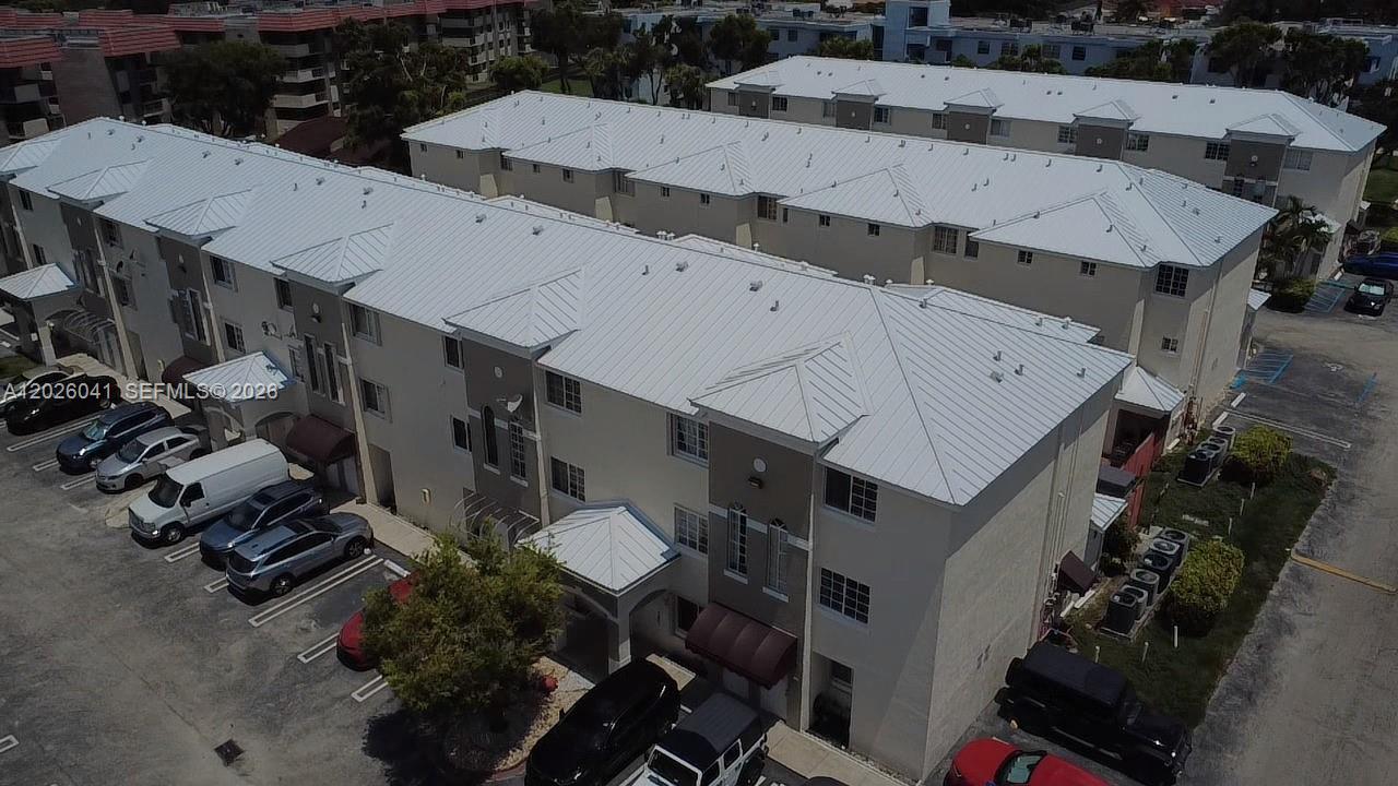 An aerial view shows multi-story apartment buildings with white metal roofs and parking lots — 12015 SW 14 st # 301-C, Miami FL 33184, MIAMI, FL