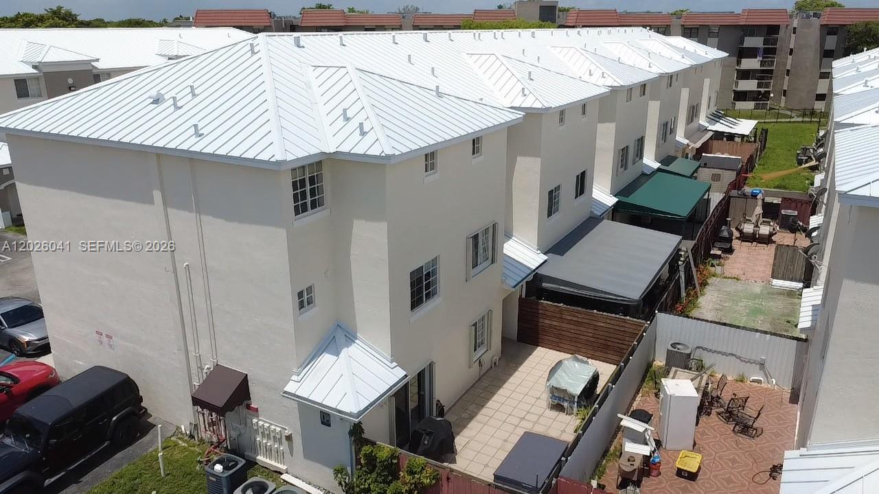 An aerial view shows the exterior of a multi-story townhouse with a metal roof — 12015 SW 14 st # 301-C, Miami FL 33184, MIAMI, FL