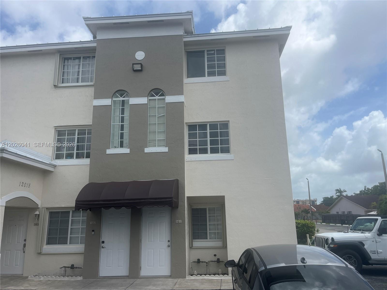 A three-story townhouse exterior features a beige facade, a gray central column, and two doors — 12015 SW 14 st # 301-C, Miami FL 33184, MIAMI, FL