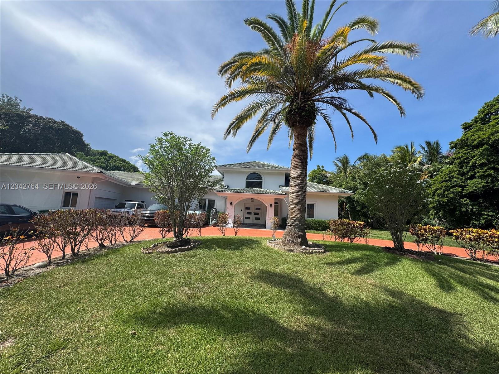 A white house with a palm tree in the front yard and a red driveway — 7935 SW 128th St, Pinecrest FL 33156, PINECREST, FL