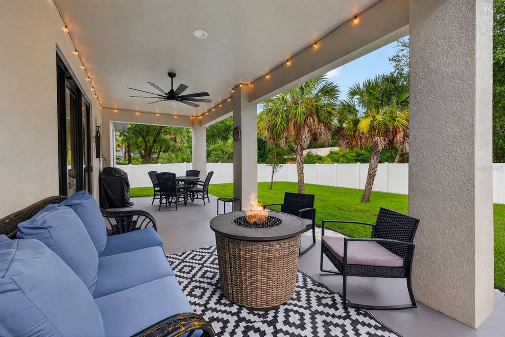 A covered patio features a fire pit, outdoor seating, and a view of the backyard — 3772 PARKINS TERRACE, NORTH PORT, FL