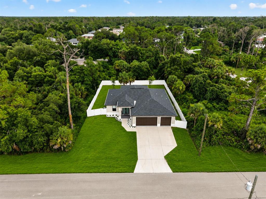 An aerial view of a single-story house with a dark roof and a concrete driveway — 3772 PARKINS TERRACE, NORTH PORT, FL