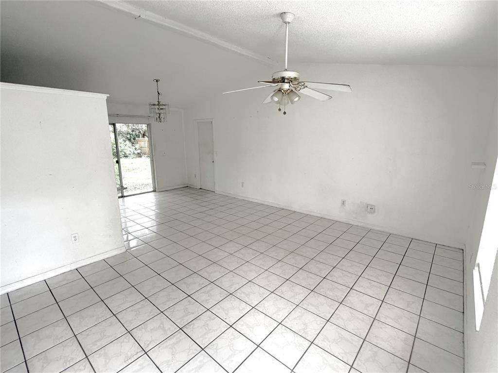 An empty room features white walls, a ceiling fan, and light-colored tiled flooring — 745 WHITEWOOD DRIVE, DELTONA, FL