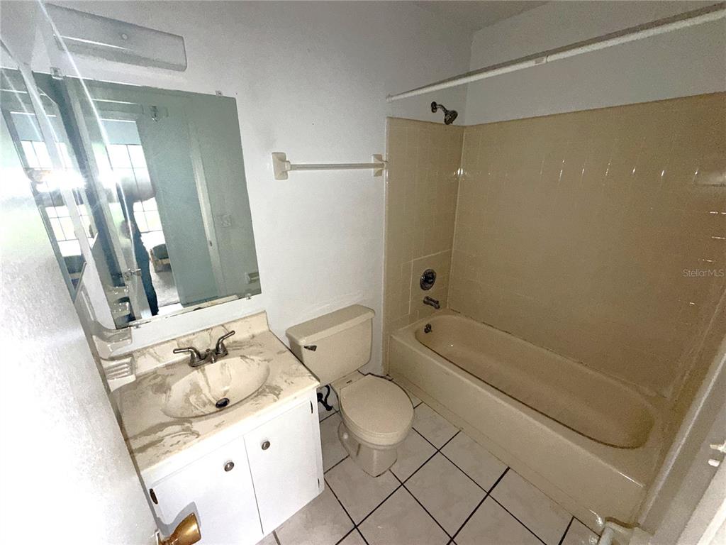 A bathroom features a vanity with a sink, a toilet, and a beige tiled tub — 745 WHITEWOOD DRIVE, DELTONA, FL