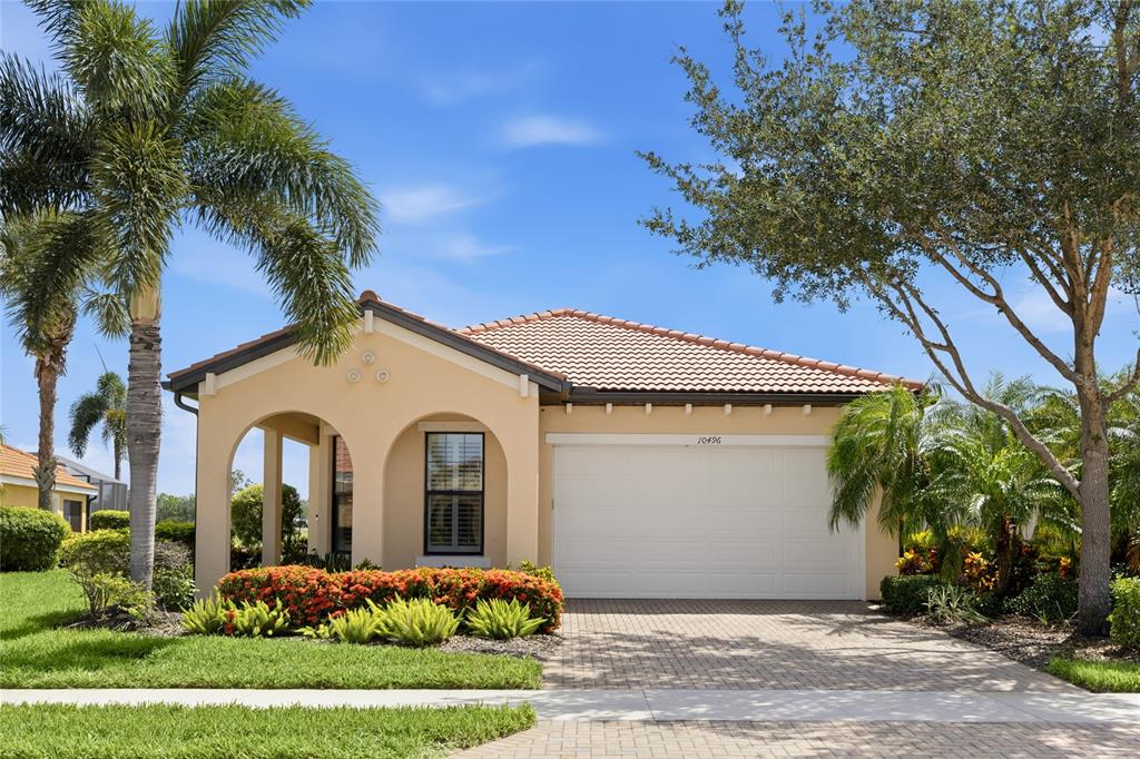 A single-story house with a tan stucco exterior, tile roof, and a two-car garage — 10496 CROOKED CREEK DRIVE, VENICE, FL