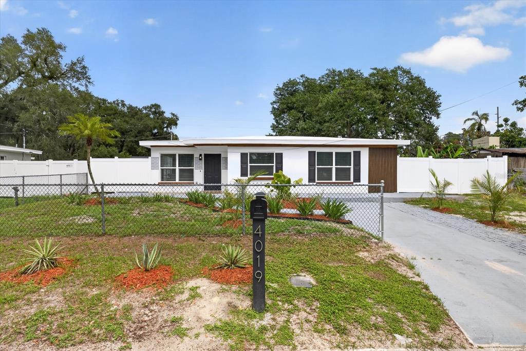 A single-story house with a white exterior, dark shutters, and a front yard with fencing — 4019 MCLANE DRIVE, TAMPA, FL