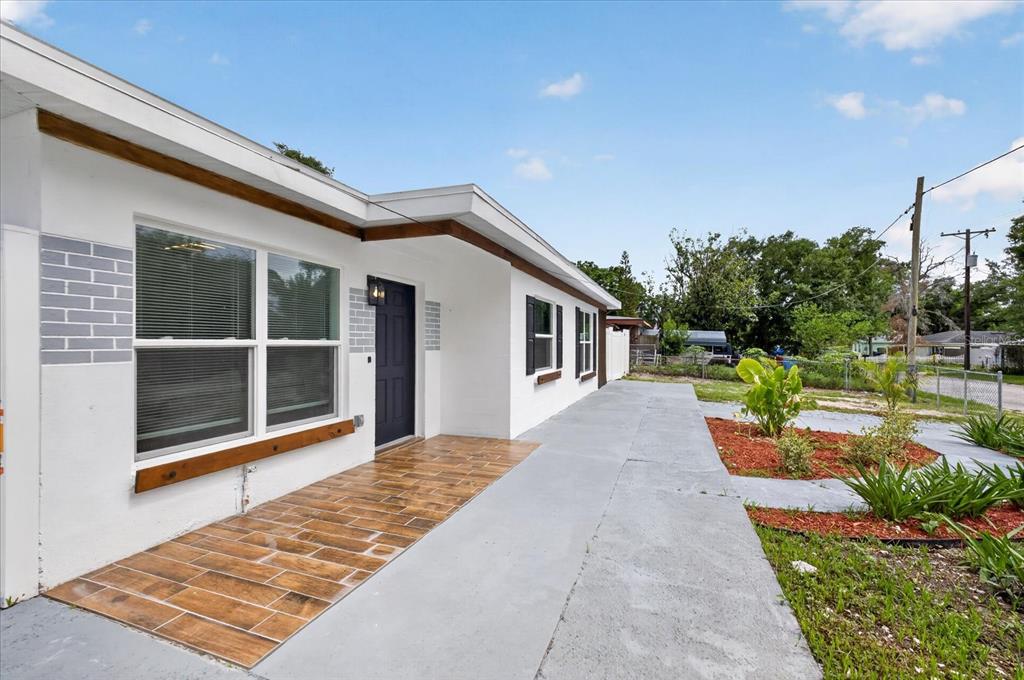 A white house exterior features a tiled front porch, dark shutters, and a gray walkway — 4019 MCLANE DRIVE, TAMPA, FL