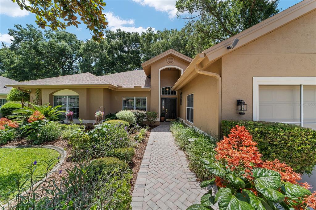 A tan single-story house features a brick walkway leading to a recessed front entryway — 11465 SW 82ND COURT ROAD, OCALA, FL