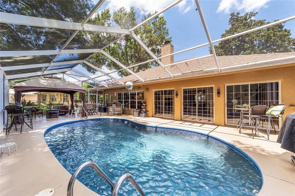 A screened-in patio features a swimming pool, outdoor furniture, and a tan house exterior — 11465 SW 82ND COURT ROAD, OCALA, FL