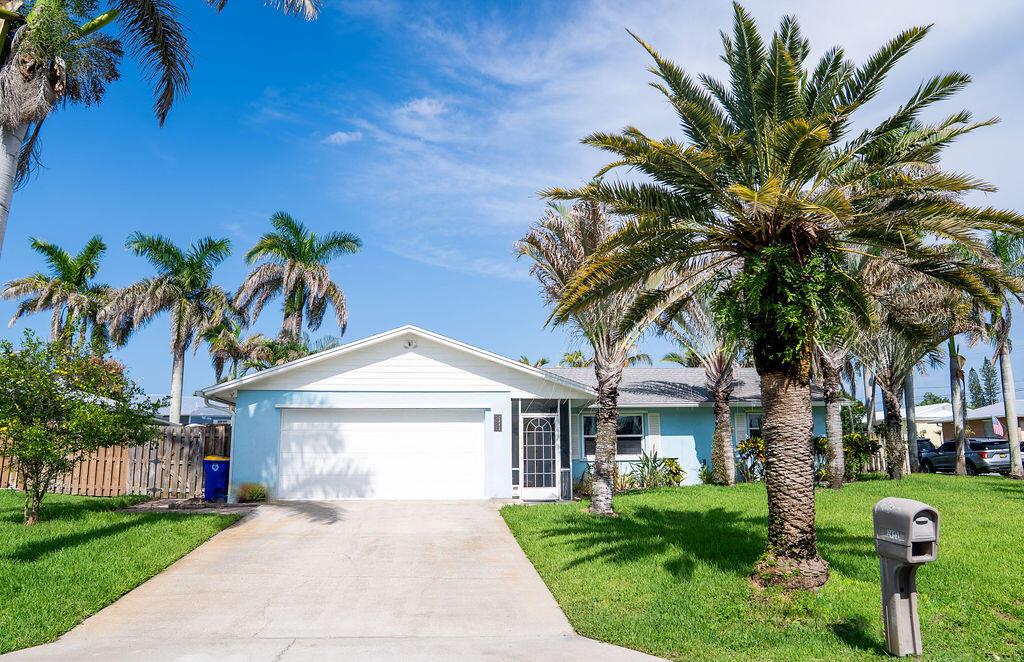 A light blue single-story house with a white garage door and palm trees in front — 2445 NE 16th Court, Jensen Beach FL 34957, JENSEN BEACH, FL