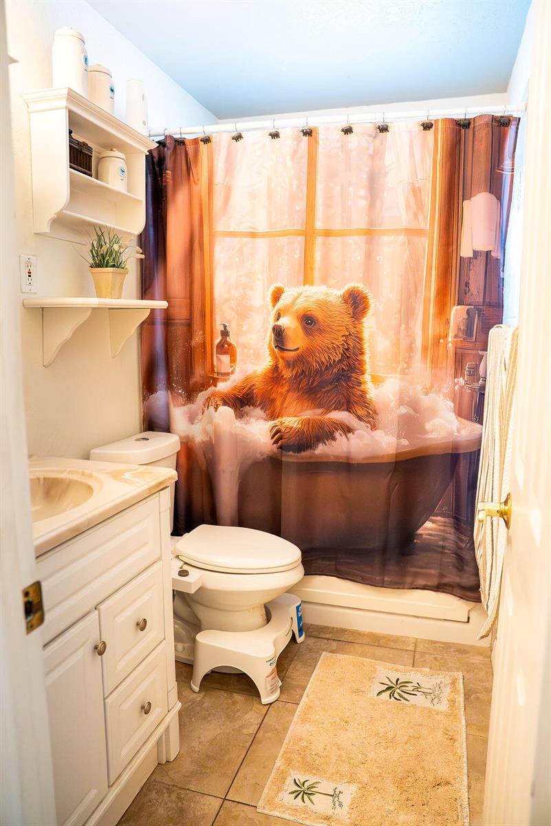 A bathroom features a vanity, toilet with a bidet attachment, and a bear-themed shower curtain — 2445 NE 16th Court, Jensen Beach FL 34957, JENSEN BEACH, FL