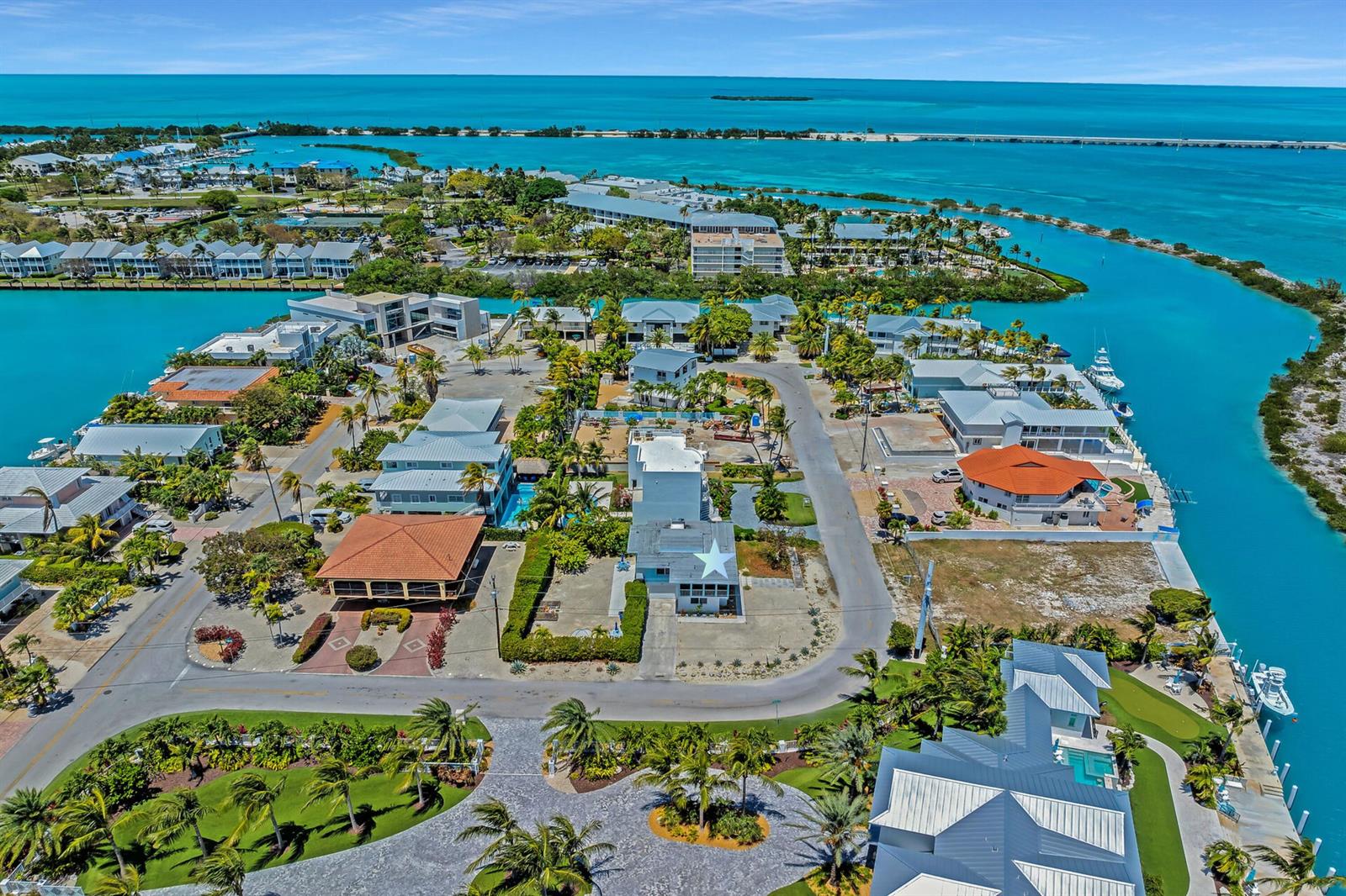 An aerial view shows a coastal neighborhood with houses, palm trees, and turquoise water — 309 Jasmine Street, FL 33050, FL