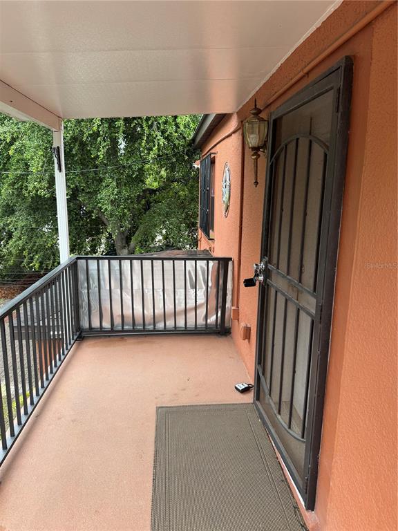 An elevated outdoor balcony features a metal security door, a railing, and a doormat — 2205 CHIPCO STREET UNIT C, TAMPA, FL