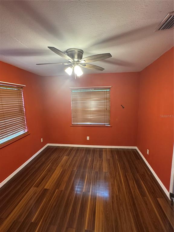 A bedroom with orange walls, wood-look flooring, two windows with blinds, and a ceiling fan — 2205 CHIPCO STREET UNIT C, TAMPA, FL