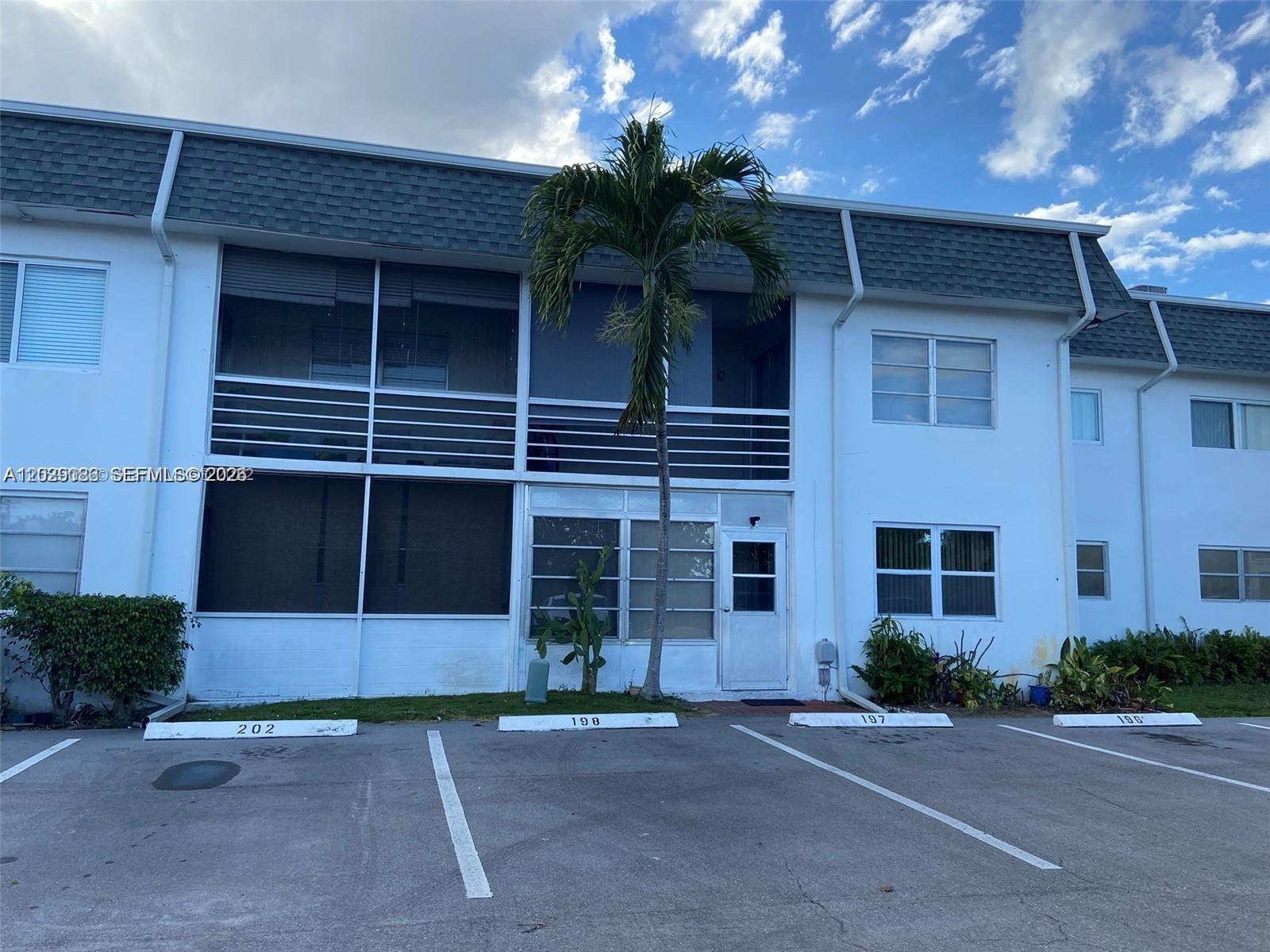 A two-story white apartment building features screened balconies and assigned parking spaces in front — 6501 Winfield Blvd # 26, Margate FL 33063, MARGATE, FL