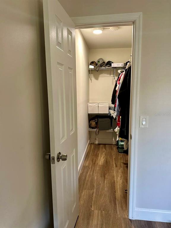 A walk-in closet with wood-look flooring, wire shelving, and hanging clothes — 2451 OAK PARK WAY UNIT 120, ORLANDO, FL