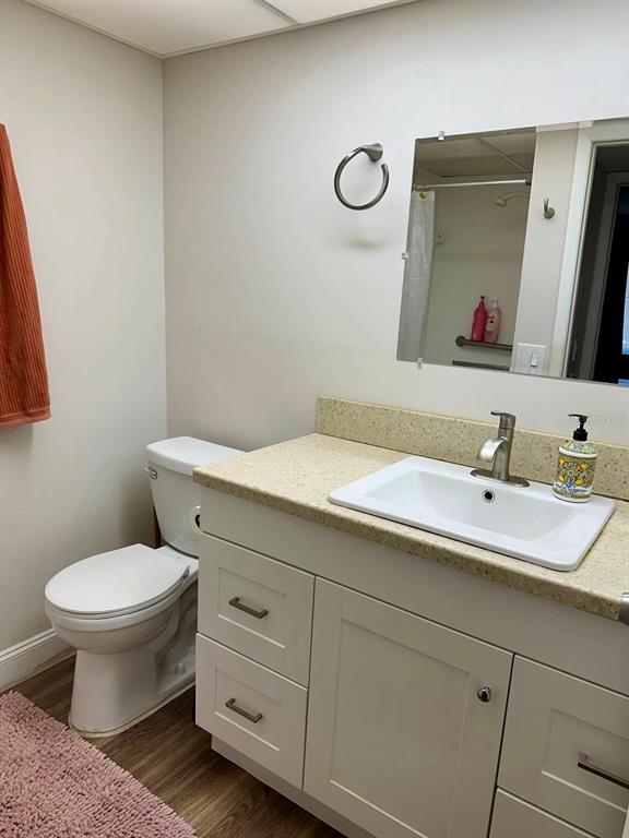 A bathroom features a white vanity with a light-colored countertop, a toilet, and a mirror — 2451 OAK PARK WAY UNIT 120, ORLANDO, FL
