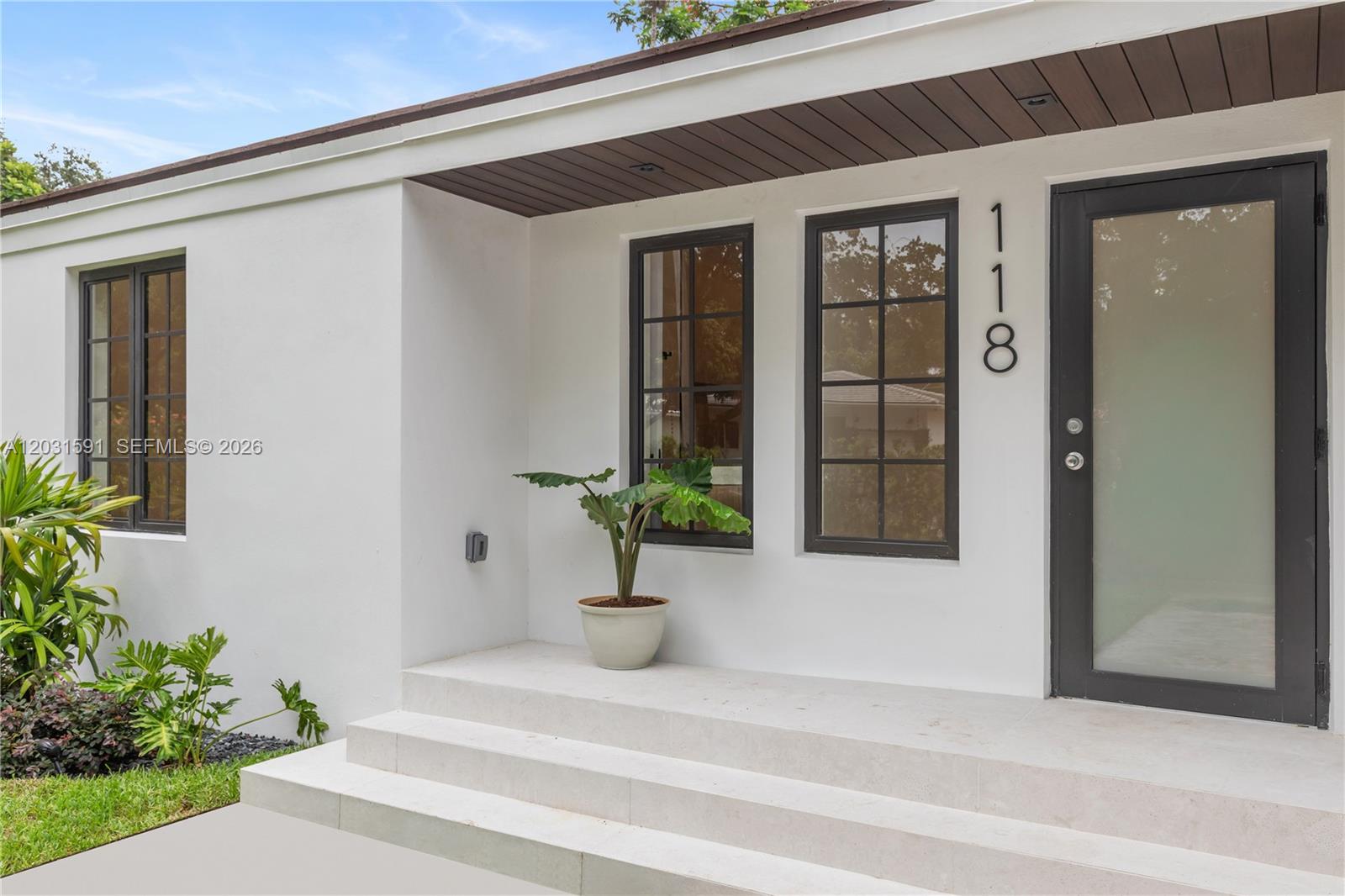 The exterior of a white house features a front porch with steps and a dark door — 118 Sarto Ave, Coral Gables FL 33134, CORAL GABLES, FL