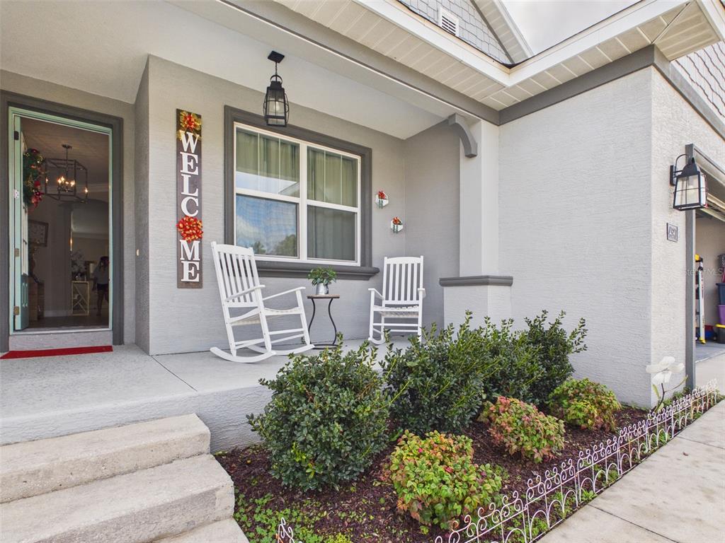 A gray house exterior features a front porch with two white rocking chairs and landscaping — 4590 SW 99TH STREET, OCALA, FL