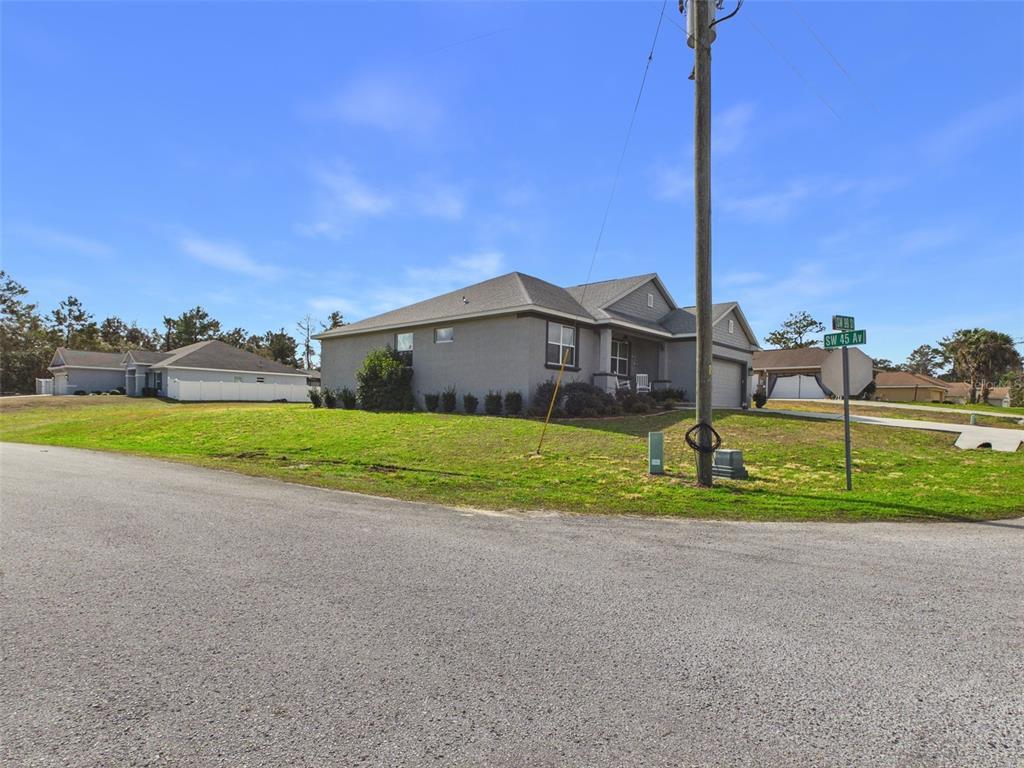 A gray single-story house with a garage sits on a corner lot with grass — 4590 SW 99TH STREET, OCALA, FL