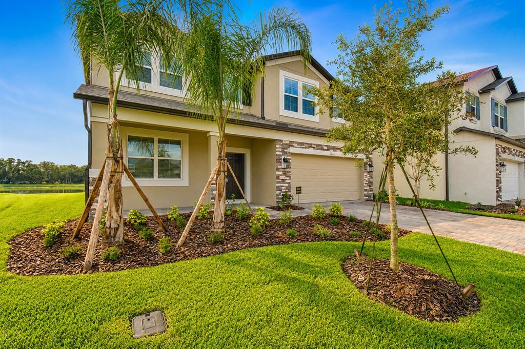 A two-story suburban house with a tan exterior, stone accents, and a two-car garage — 38190 SHALE STONE COURT, ZEPHYRHILLS, FL