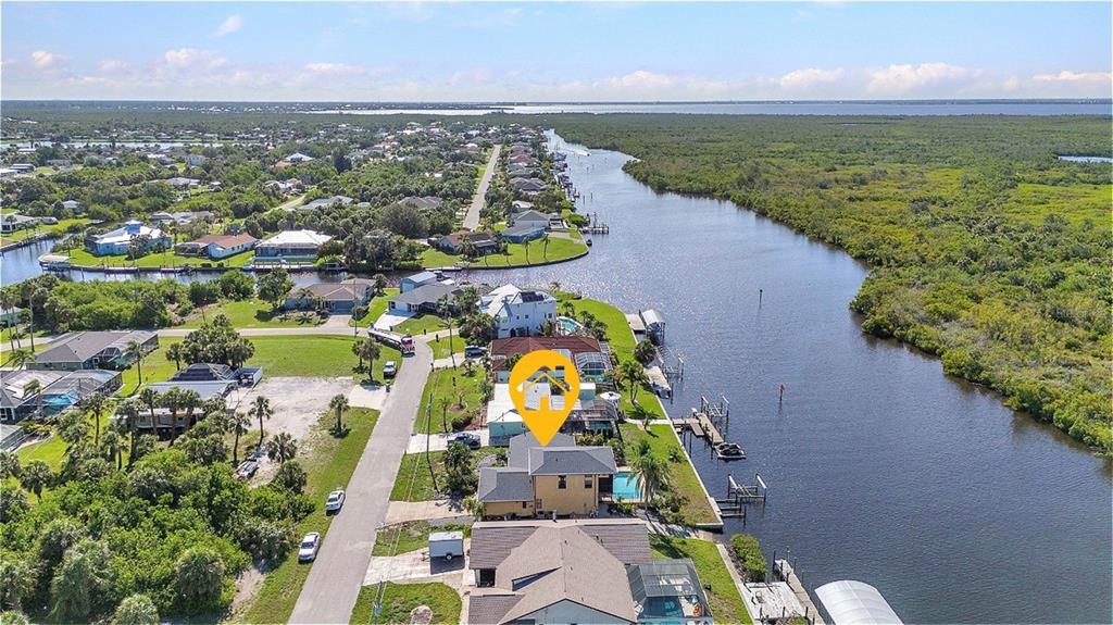 An aerial view shows a waterfront house with a pool along a canal and mangroves — 18566 ARAPAHOE CIRCLE, PORT CHARLOTTE, FL