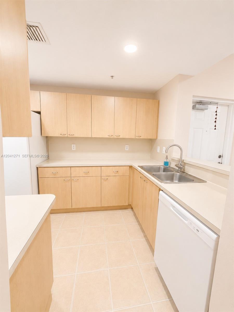This kitchen features light wood cabinets, white countertops, a double sink, and tile flooring — 6670 NW 114th Ave # 603, Doral FL 33178, DORAL, FL