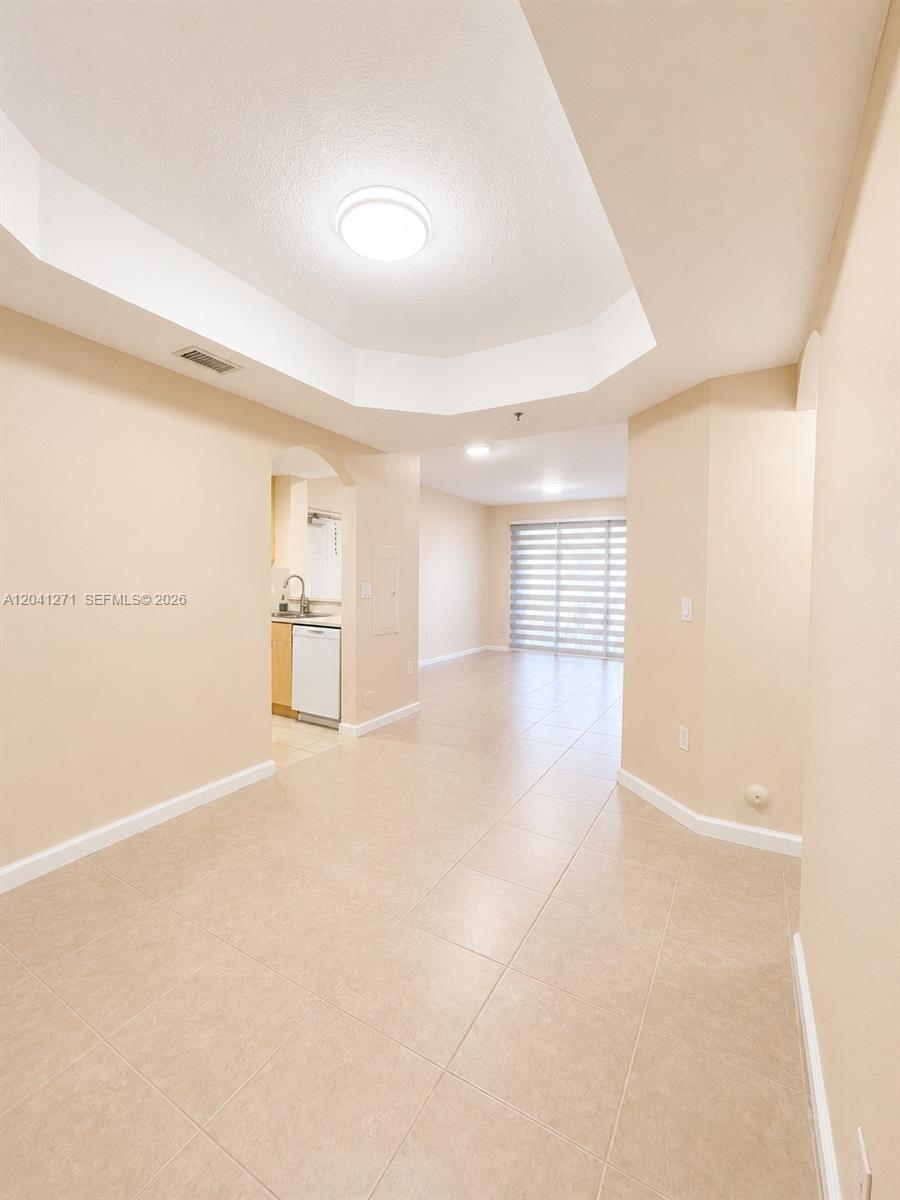 A bright, tiled living area features a tray ceiling and an adjacent kitchen — 6670 NW 114th Ave # 603, Doral FL 33178, DORAL, FL