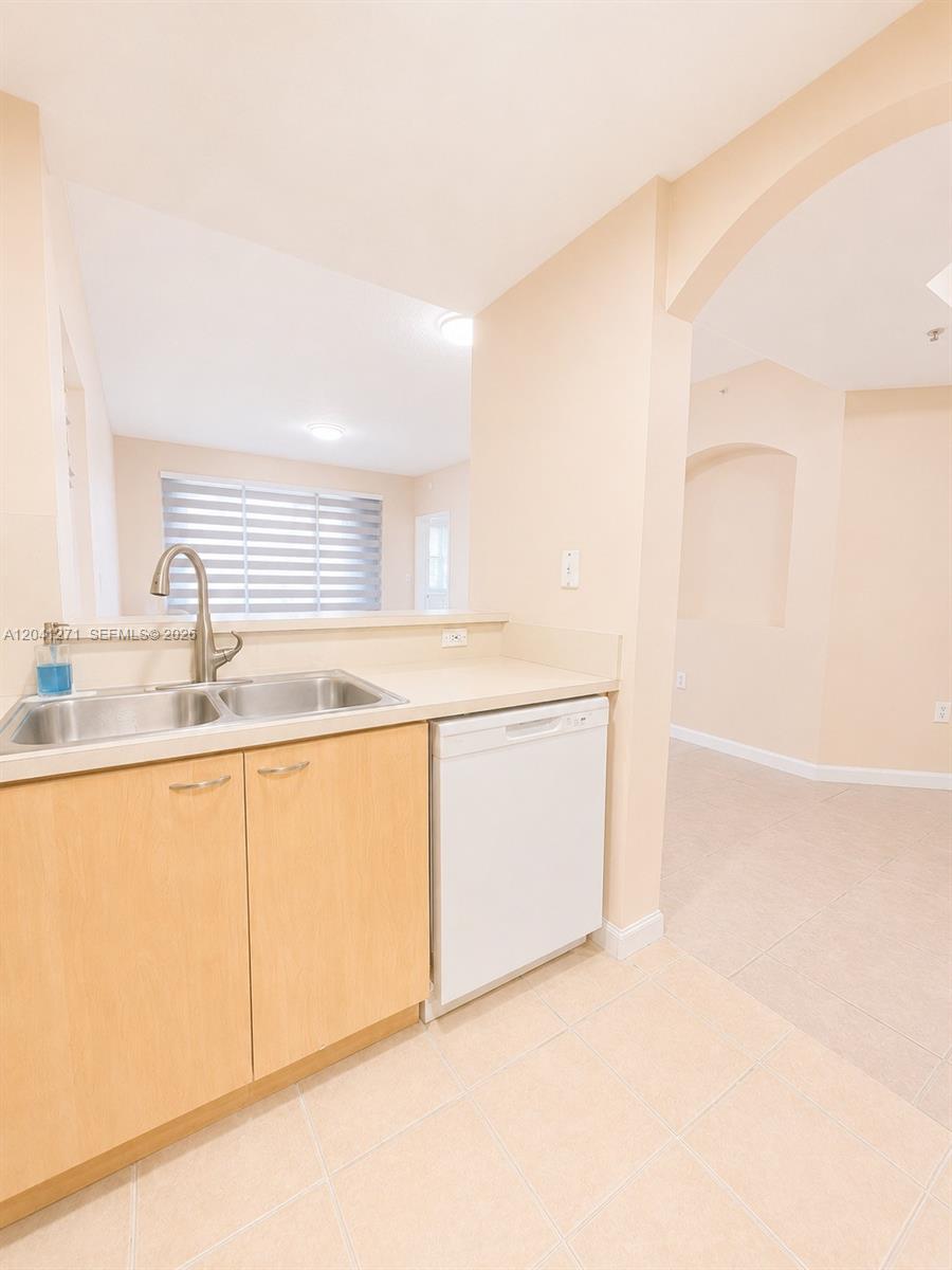 A kitchen features light wood cabinets, a stainless steel sink, and a white dishwasher — 6670 NW 114th Ave # 603, Doral FL 33178, DORAL, FL