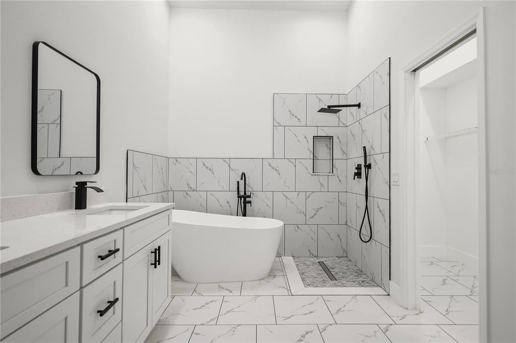 A modern bathroom features a white soaking tub, a walk-in shower, and a marble-topped vanity — 14510 QUAIL TRAIL CIRCLE, ORLANDO, FL