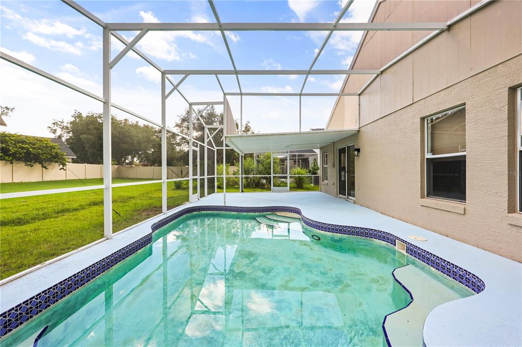 A swimming pool with a blue tiled border sits inside a screened-in patio enclosure — 14510 QUAIL TRAIL CIRCLE, ORLANDO, FL