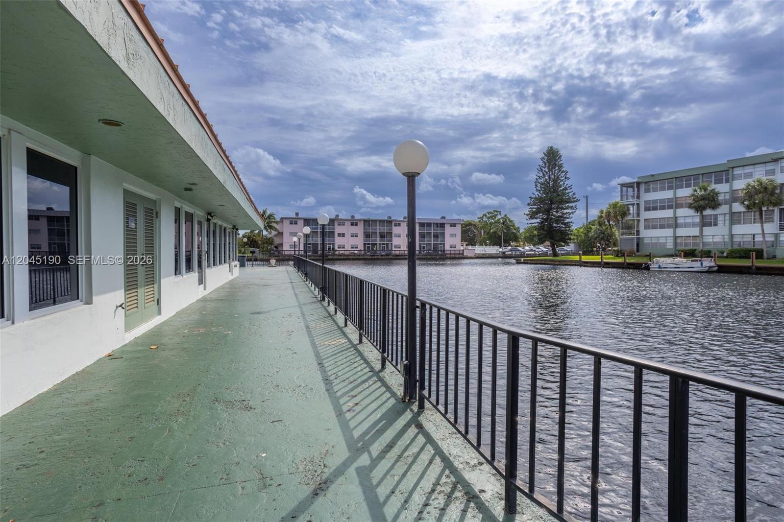 A green walkway with a black metal railing overlooks a canal and apartment buildings — 2771 Taft St # 104, Hollywood FL 33020, HOLLYWOOD, FL
