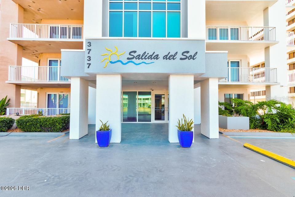 The exterior of a multi-story residential building features a covered entrance with two blue planters — 3737 S ATLANTIC AVENUE UNIT 401, DAYTONA BEACH SHORES, FL