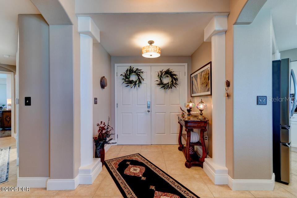 An entryway features white double doors, two decorative columns, a runner rug, and a console table — 3737 S ATLANTIC AVENUE UNIT 401, DAYTONA BEACH SHORES, FL
