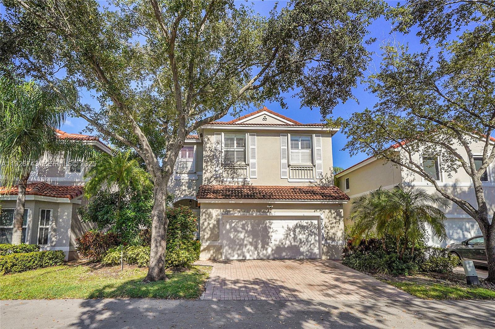 A kitchen with dark wood cabinets and a white island opens into a living area — 1135 Satinleaf St, Hollywood FL 33019, HOLLYWOOD, FL