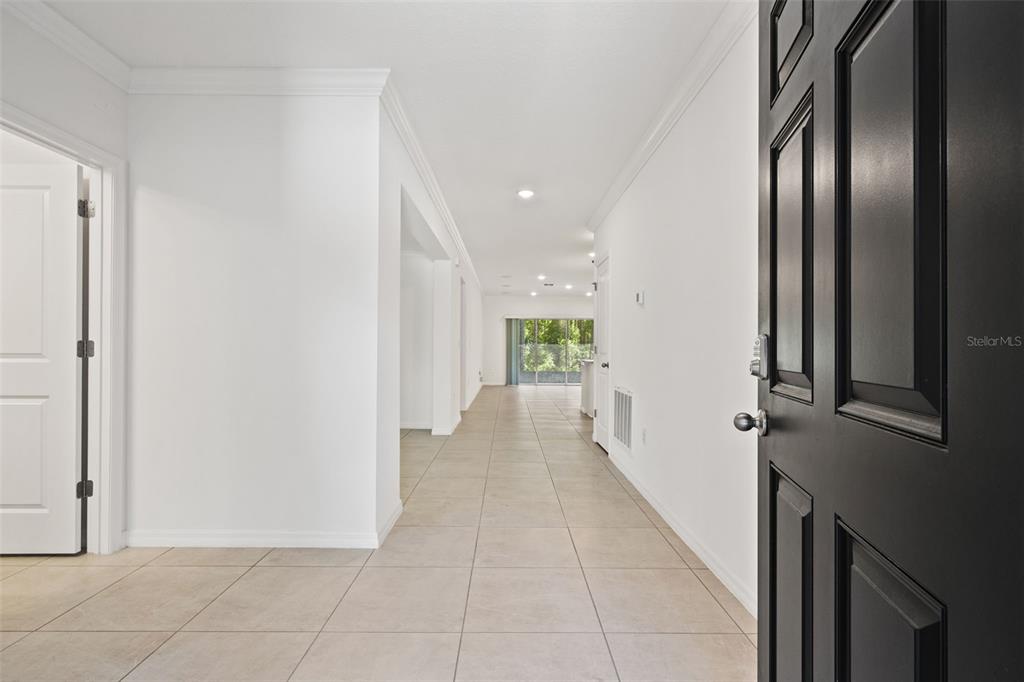 An entryway with tile flooring leads down a hallway toward a bright living area — 13296 THRASHER AVENUE, WEEKI WACHEE, FL