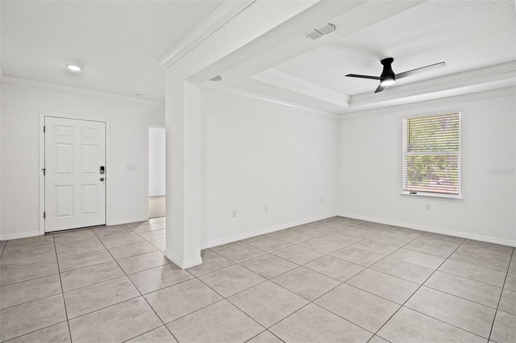 A bright, empty room features white walls, large gray floor tiles, and a tray ceiling — 13296 THRASHER AVENUE, WEEKI WACHEE, FL