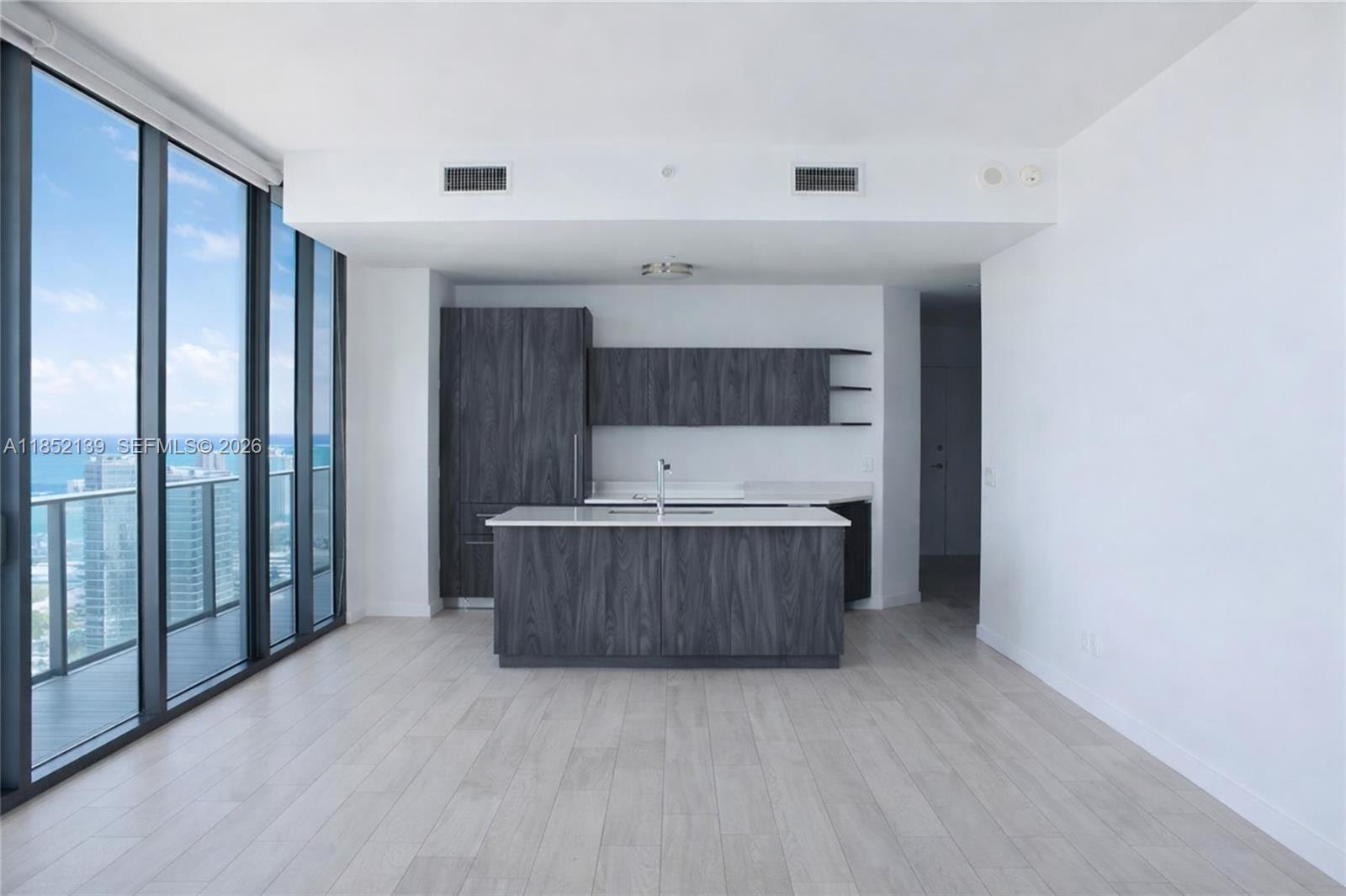 A modern kitchen features dark wood cabinetry, a central island, and floor-to-ceiling windows — 480 NE 31st St # 3301, Miami FL 33137, MIAMI, FL