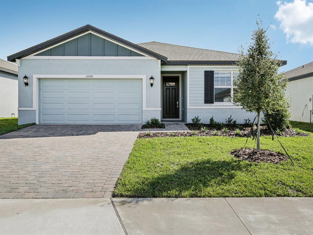 A single-story house with a light blue exterior, a two-car garage, and a paved driveway — 13310 SHELLMORE AVENUE, PALMETTO, FL