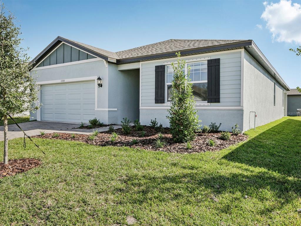 A single-story house with light blue siding, a two-car garage, and a landscaped front yard — 13310 SHELLMORE AVENUE, PALMETTO, FL