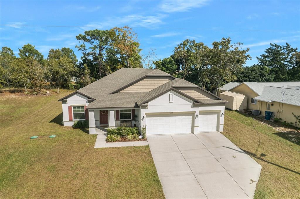 An aerial view of a single-story house with a white stucco facade and attached garage — 6283 GRAPEWOOD ROAD, SPRING HILL, FL