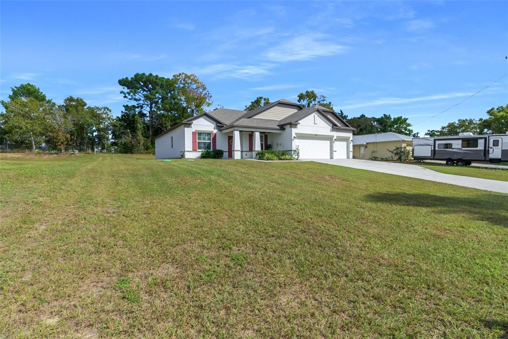 A single-story house with a white exterior, red shutters, and a two-car garage — 6283 GRAPEWOOD ROAD, SPRING HILL, FL