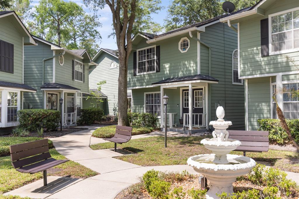A courtyard with a fountain and benches sits between green multi-story apartment buildings — 5990 BRAEMAR PLACE UNIT 106, ORLANDO, FL