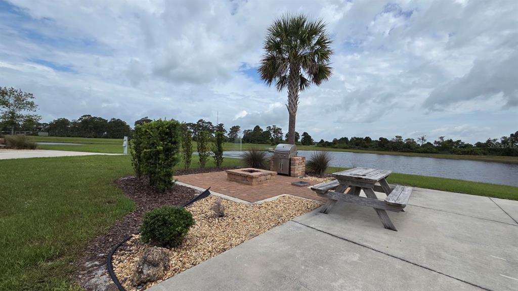 An outdoor patio features a brick fire pit, a grill, and a wooden picnic table — 71 CEDAR CIRCLE E, LAKE WALES, FL