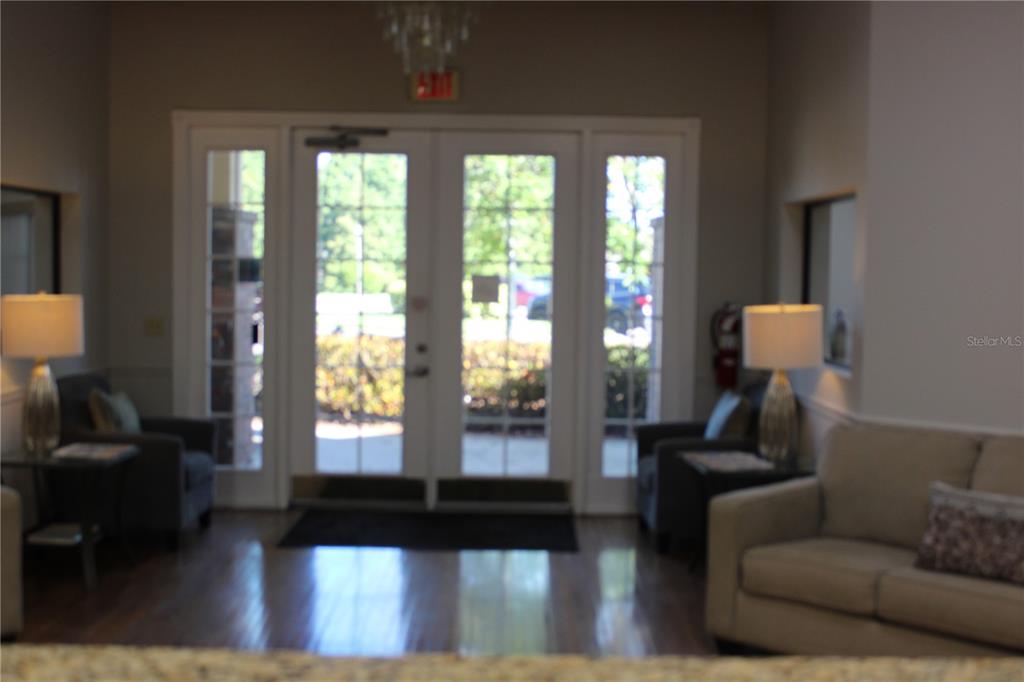A lobby area features double glass doors, two armchairs, a sofa, and two table lamps — 4175 WOODLANDS PARKWAY UNIT 26, PALM HARBOR, FL