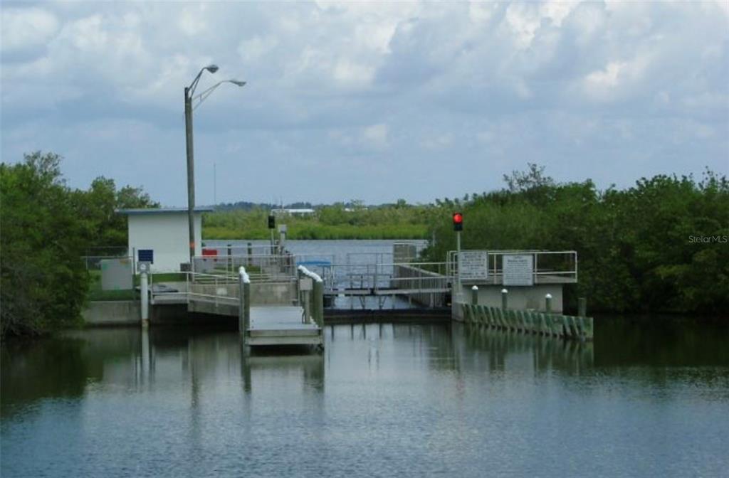 A boat lock structure with a red signal light sits on a calm waterway — 14634 INGRAHAM BOULEVARD, PORT CHARLOTTE, FL