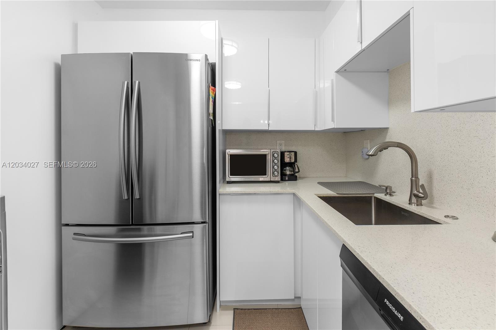 A modern kitchen features white cabinets, stainless steel appliances, and light-colored countertops — 1849 S Ocean Dr # 212, Hallandale Beach FL 33009, HALLANDALE BEACH, FL