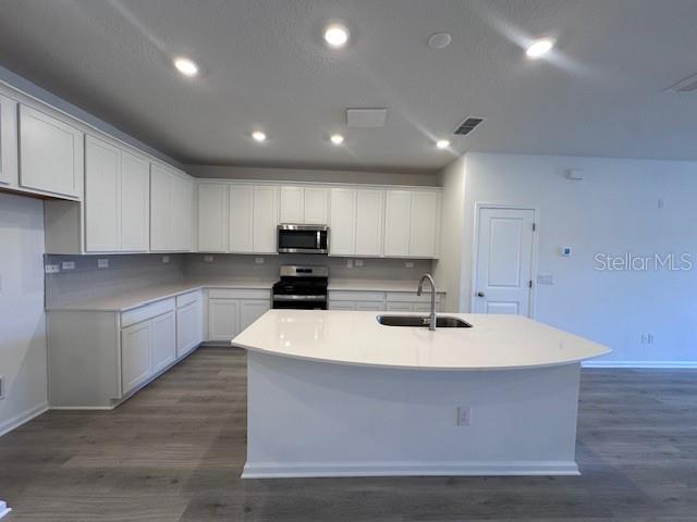 A modern kitchen features white cabinetry, a large island with a sink, and light flooring — 382 WOODS LANE, ST AUGUSTINE, FL