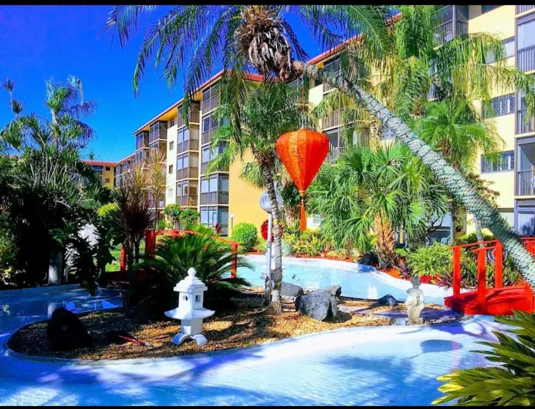 An exterior view of a multi-story apartment building with a pool, palm trees, and bridge — 2601 NE 14th St Causeway # 233, Pompano Beach FL 33062, POMPANO BEACH, FL
